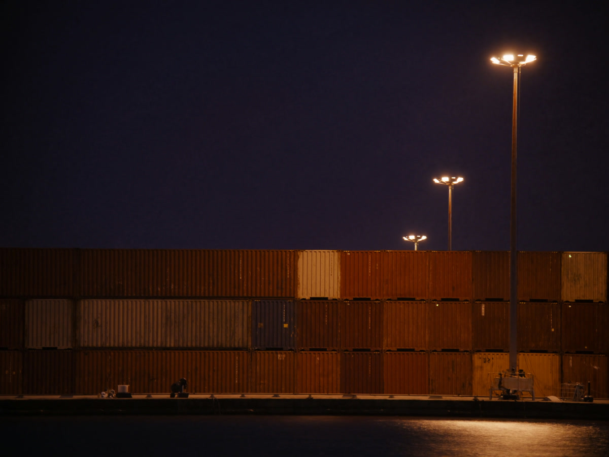 Contêineres organizados no pátio do porto sob luz noturna